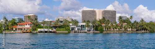 Miami Beach, Florida- Villas and modern buildings in intracoastal waterway at Biscayne Bay. Panorama of blue waterway at the front near the villas and modern buildings against the cloudy sky. © Jason