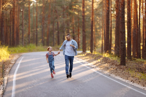 Wallpaper Mural Dad and his little daughter have fun run along the forest road among tall pines. Family walk in the forest at sunset, a man and a little girl. Torontodigital.ca