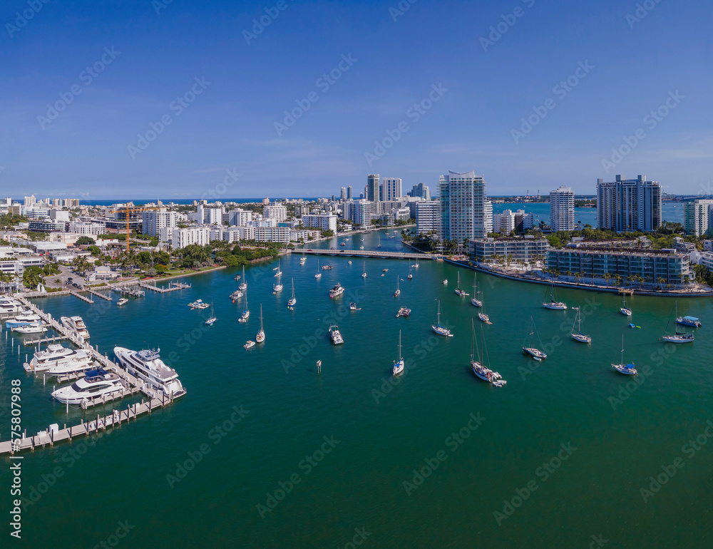 Aerial view of Intracoastal Waterway with boats and buildings in Miami Florida. Urban city landscape with scenic skyline and man-made inland water channel against blue sky.