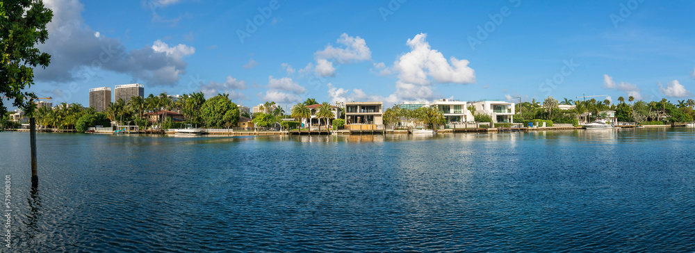 Miami Beach, Florida- intracoastal waterway residential area at Biscayne Bay panorama. There are waterfront two-storey houses with private docks near the modern buildings on the left.