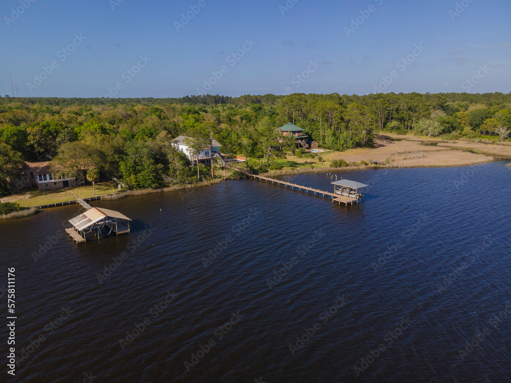 Three villas near the forest with private docks and boat lifts on its waterfront in Navarre, Florida. Intracoastal forest residential area with clear blue sky background.