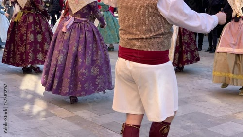 Group of people dressed in the traditional clothing of the festival of fallas performing a typical dance. Valencia, Spain photo