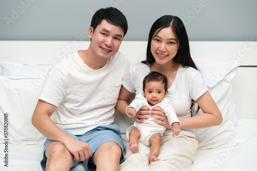 happy family (father and mother and baby) on bed