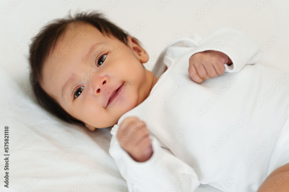 happy newborn baby smilling while lying on a bed happy newborn baby smilling while lying on a bed
