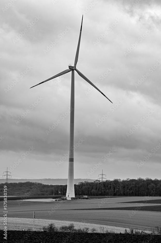 Windrad steht im Winter auf einem Feld bei Werneck, Deutschland in schwarz-weiss 12.02.2023