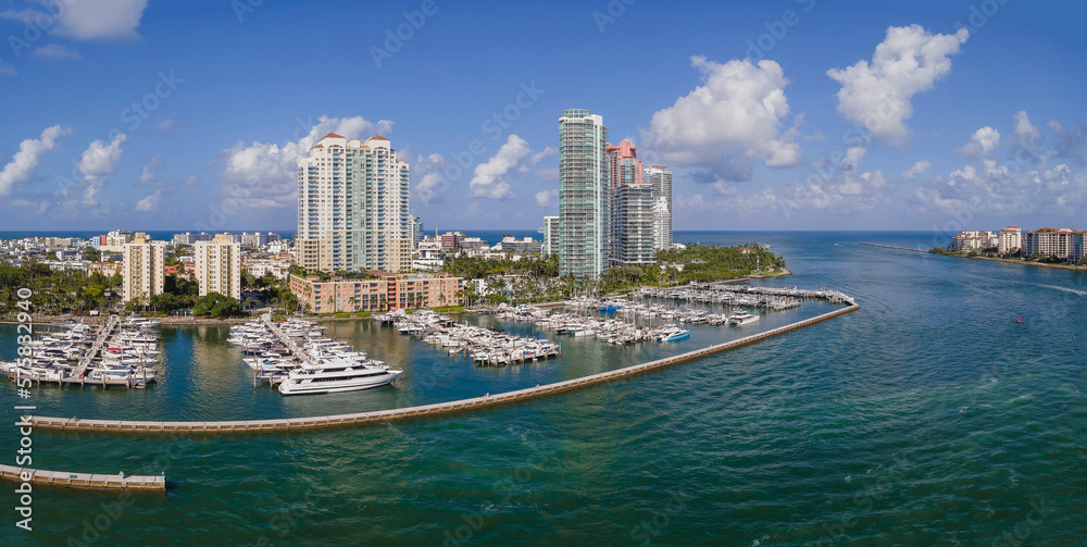 White boats docked at Meloy Channel at Intracoastal Waterway in Miami Florida. Spectacular city skyline against blue sky with condominiums and buildings overlooking the manmade channel.
