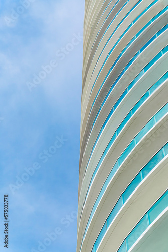 Round apartment building with glass balcony railings in Miami, Florida. Low angle vertical shot view of a modern apartment building against the sky.