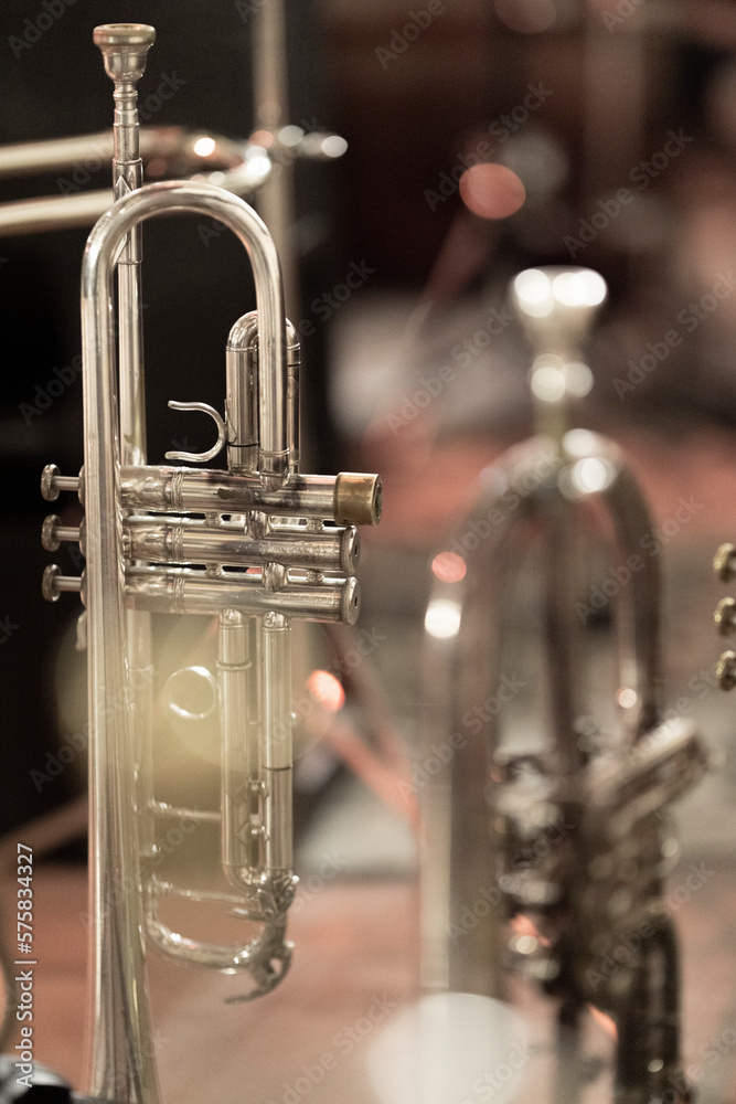 Obraz premium A silver plated trumpet with a mouthpiece standing behind a flugelhorn