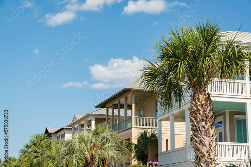 Row of houses with balconies with palm trees view at the front in Destin, Florida. There are palm trees at the front of the houses under the sky. © Jason