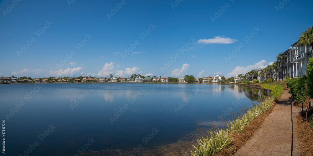 View of Four Prong Lake from a bricks pathway near the residences at Destin, Florida. Panorama of lakefront houses with pathway at front and blue sky background.