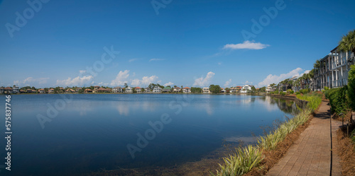 View of Four Prong Lake from a bricks pathway near the residences at Destin, Florida. Panorama of lakefront houses with pathway at front and blue sky background.