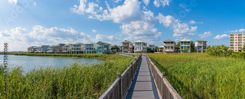 Homes on the beach with lake and footbridge at the front in Destin Point, Destin, Florida. There is a multi-storey apartment on the right along with the lakefront three-storey houses on the left.