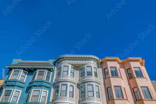 Photography Charming homes with bay windows and colorful walls against vibrant blue sky