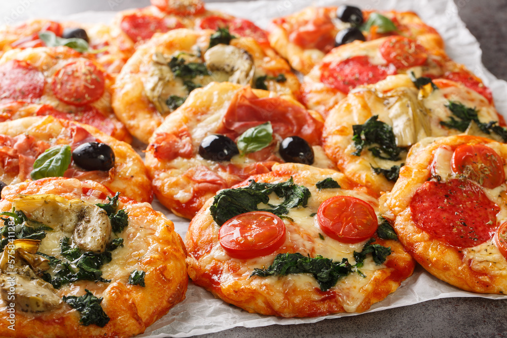 Pizzette Italian mini pizzas or pizza bites close-up on parchment on the table. Horizontal Pizzette Italian mini pizzas or pizza bites close-up on parchment on the table. Horizontal