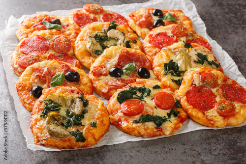 Italian Pizzette Mini Pizza Bites With Assorted Toppings close-up on parchment on the table. Horizontal photo