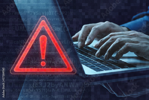 Security alert of computer. Exclamation icon and laptop. Close up of hands typing.