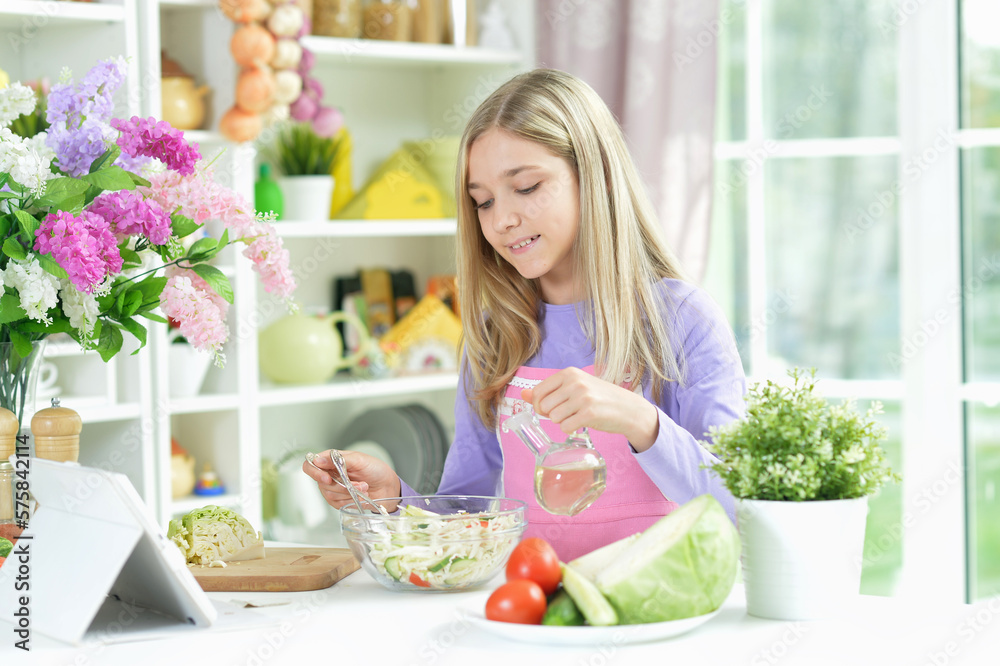 girl preparing fresh salad on kitchen table with tablet at home girl preparing fresh salad on kitchen table with tablet at home
