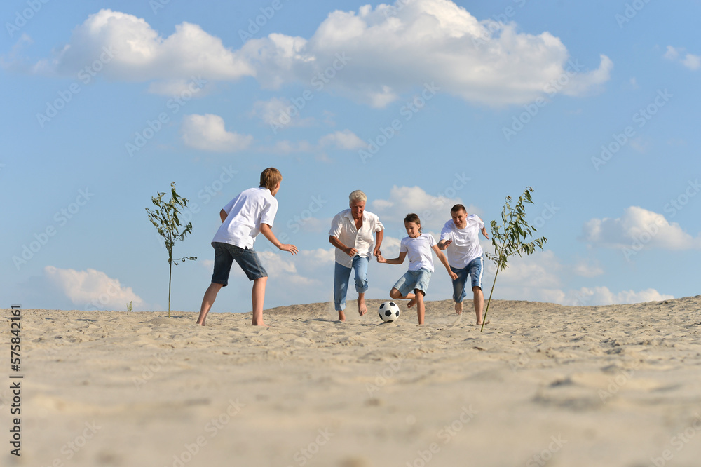 Family playing football on a beach in summer day Family playing football on a beach in summer day