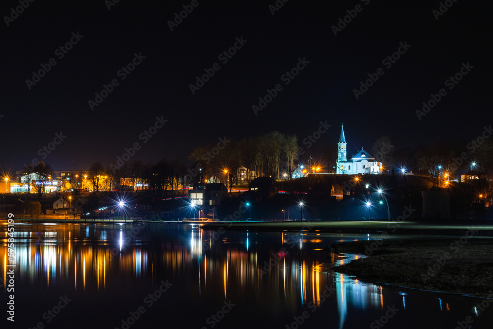 Telsiai town,water night lake in Lithuania. Nice view winter of colorful houses on coast of frozen Lake.Nice winter night.Town colorful light reflections on water.Long exposure.