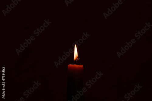 One light candle burning brightly in the dark background.Copy space.