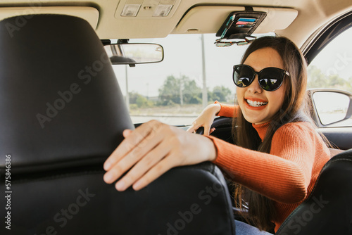 Happy beautiful young asian newbie girl in sunglasses preparing for driving lesson taught by expert instructors from driving school to drive safely on roads according to traffic rules.