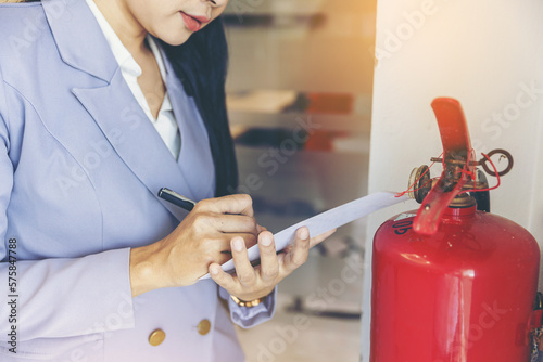 woman worker inspection chemical Fire extinguisher and fire hose. writing on monthly check document. Selected focus 