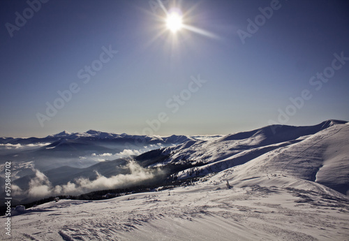 Bright sun above snowy mountain slopes and clouds landscape photo. Ski resort. Nature scenery photography. Ambient light. High quality picture for wallpaper, travel blog, magazine, article