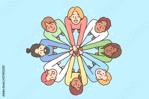 Multiracial people stand in circle with hands outstretched to demonstrate friendship