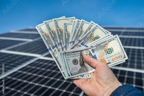 worker is holding a round amount of money for the installation of solar panels in his hands.