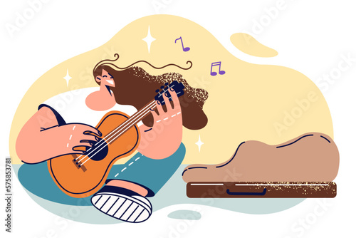 Woman street musician sings sits on ground and plays guitar to give good mood others