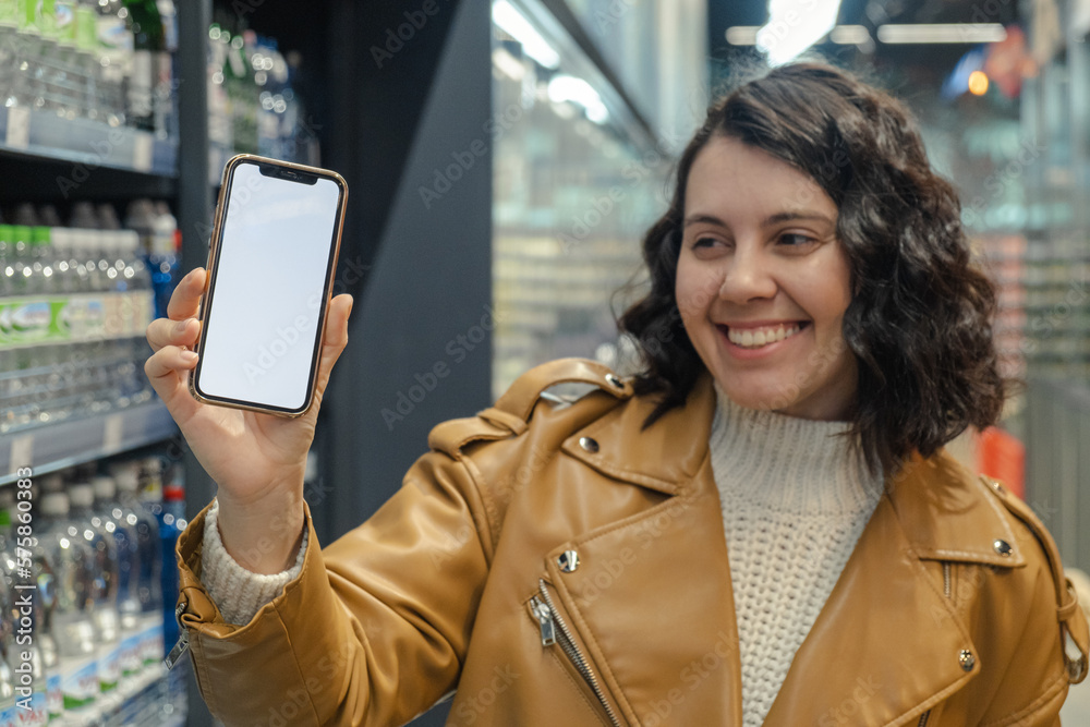 A gorgeous woman with a white-screened phone is in a supermarket. A gorgeous woman with a white-screened phone is in a supermarket.