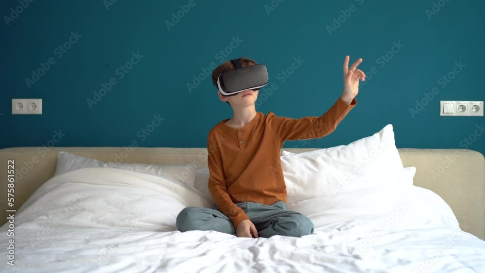 Interested child boy wearing VR glasses touching objects in virtual world use goggles mobile app. Schoolboy interacting with digital 3D interface for education or simulation selecting game menu items.