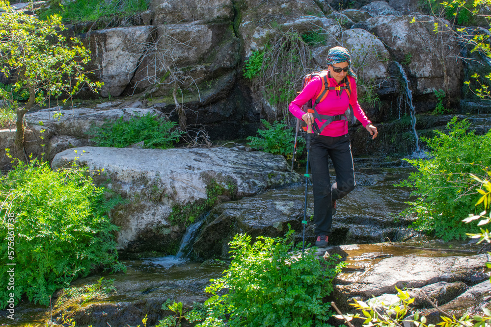 woman hiker crossing a river by the rocks