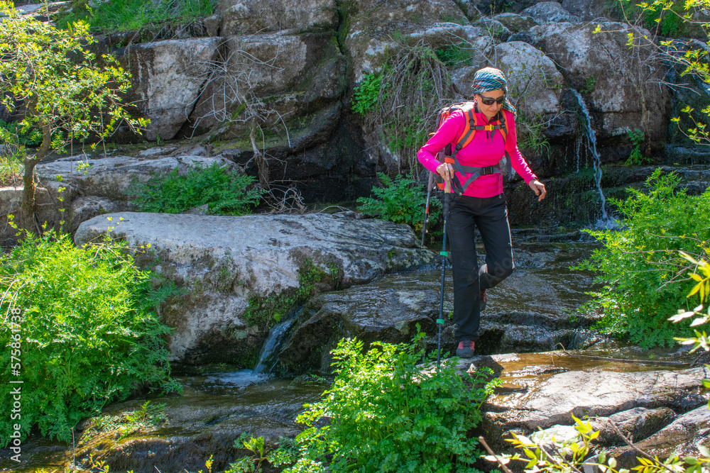 woman hiker crossing a river by the rocks woman hiker crossing a river by the rocks