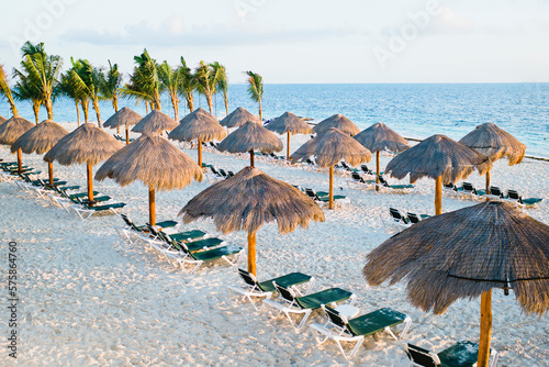 Tropical beach with thatched umbrellas and lounge chairs, Cancun, Mexico photo
