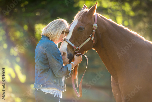 A woman an her horse in a sunny paddock
