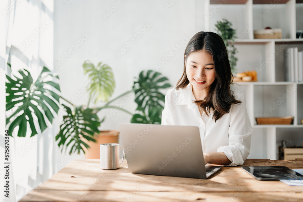 Beautiful Asian business woman typing laptop and tablet Placed at the table at home office. Beautiful Asian business woman typing laptop and tablet Placed at the table at home office.