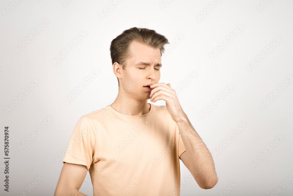 A young blond guy has an allergy and he sneezes on a white background. A young blond guy has an allergy and he sneezes on a white background.