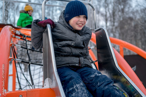 Boy playing on slide in playground at winter park photo