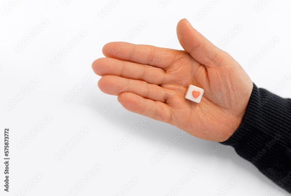 Sugar cube with red heart in hand on white background. medicine concept. diabetes concept Sugar cube with red heart in hand on white background. medicine concept. diabetes concept