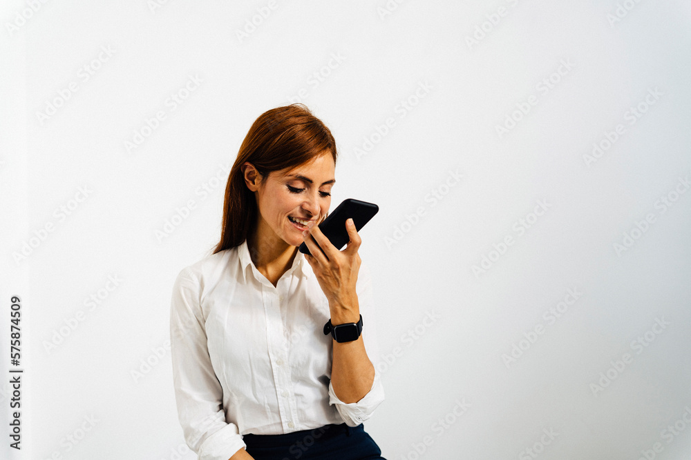 Happy businesswoman talking on smart phone in front of white wall Happy businesswoman talking on smart phone in front of white wall
