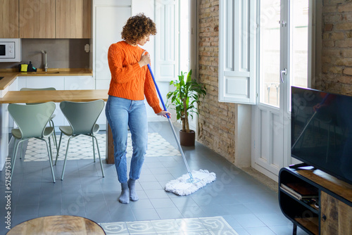 Woman with mop cleaning on floor at home