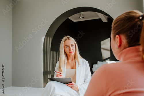 Psychologist taking notes in counseling session at clinic photo