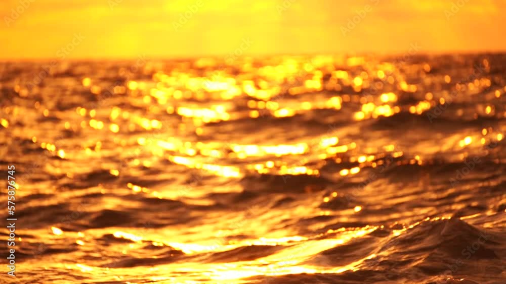 Blurred golden sea at sunset. The sun reflects and sparkles on the waves with bokeh, illuminating the golden sea. Holiday recreation concept. Abstract nautical summer ocean sunset nature background