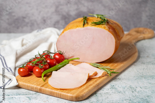 Smoked turkey meat sliced. Smoked turkey/ham fillets on a wood serving board. Deli products.