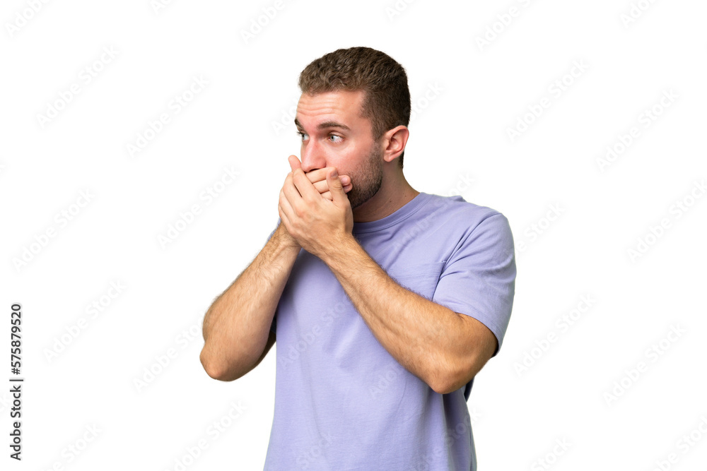 Young handsome caucasian man isolated on green chroma background covering mouth and looking to the side Young handsome caucasian man isolated on green chroma background covering mouth and looking to the side