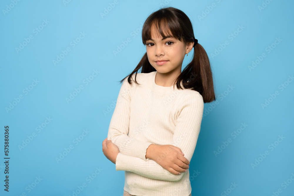 Photo of attractive little girl look empty space folded arms wear sweater isolated on blue color background Photo of attractive little girl look empty space folded arms wear sweater isolated on blue color background