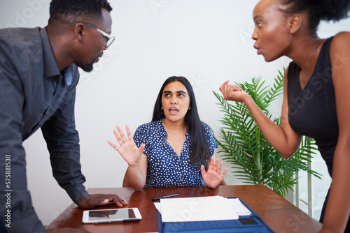 A mediator tries to keep the peace during argument, office boardroom. Divorce, arbitration photo