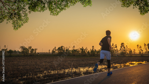 Young fitness asian man is running and jogging an outdoor workout on the road in the morning for lifestyle health.