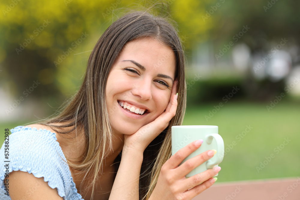 Candid happy teen looks at you holding coffee mug Candid happy teen looks at you holding coffee mug